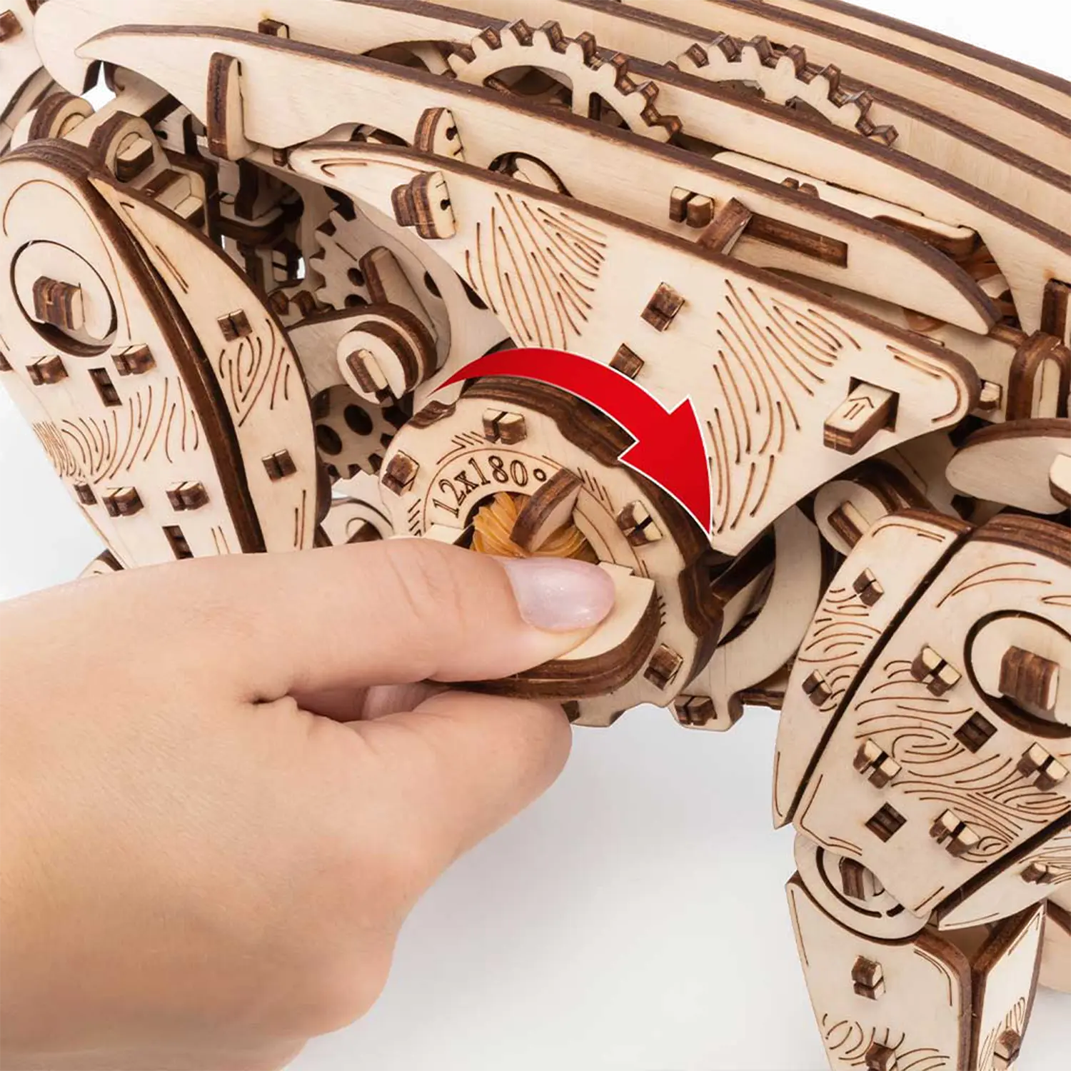 Eine Hand dreht ein hölzernes Zahnrad auf dem 3D-Holzpuzzle Mechanische Katze, natur.