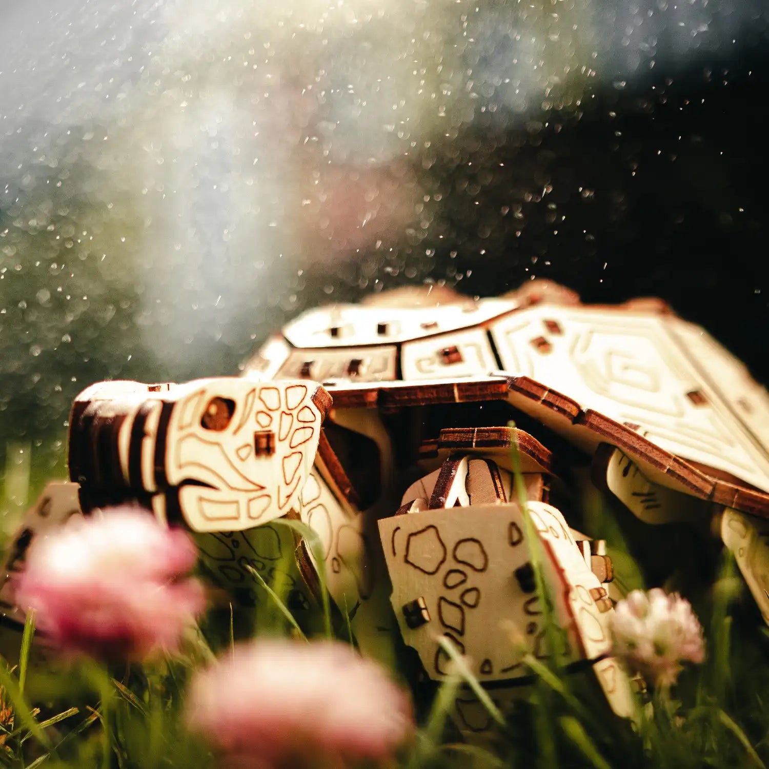 Eine skurrile Szene zeigt eine Holzspielzeugschildkröte, ähnlich dem „3D-Holzpuzzle, Mechanische Schildkröte“, auf Gras inmitten verschwommenen rosa Blüten und Tropfen. Ihre komplizierten geometrischen Muster verleihen dem schimmernden Hintergrund einen künstlerischen Touch, als wären die Teile des 3D-Puzzles lebendig geworden.