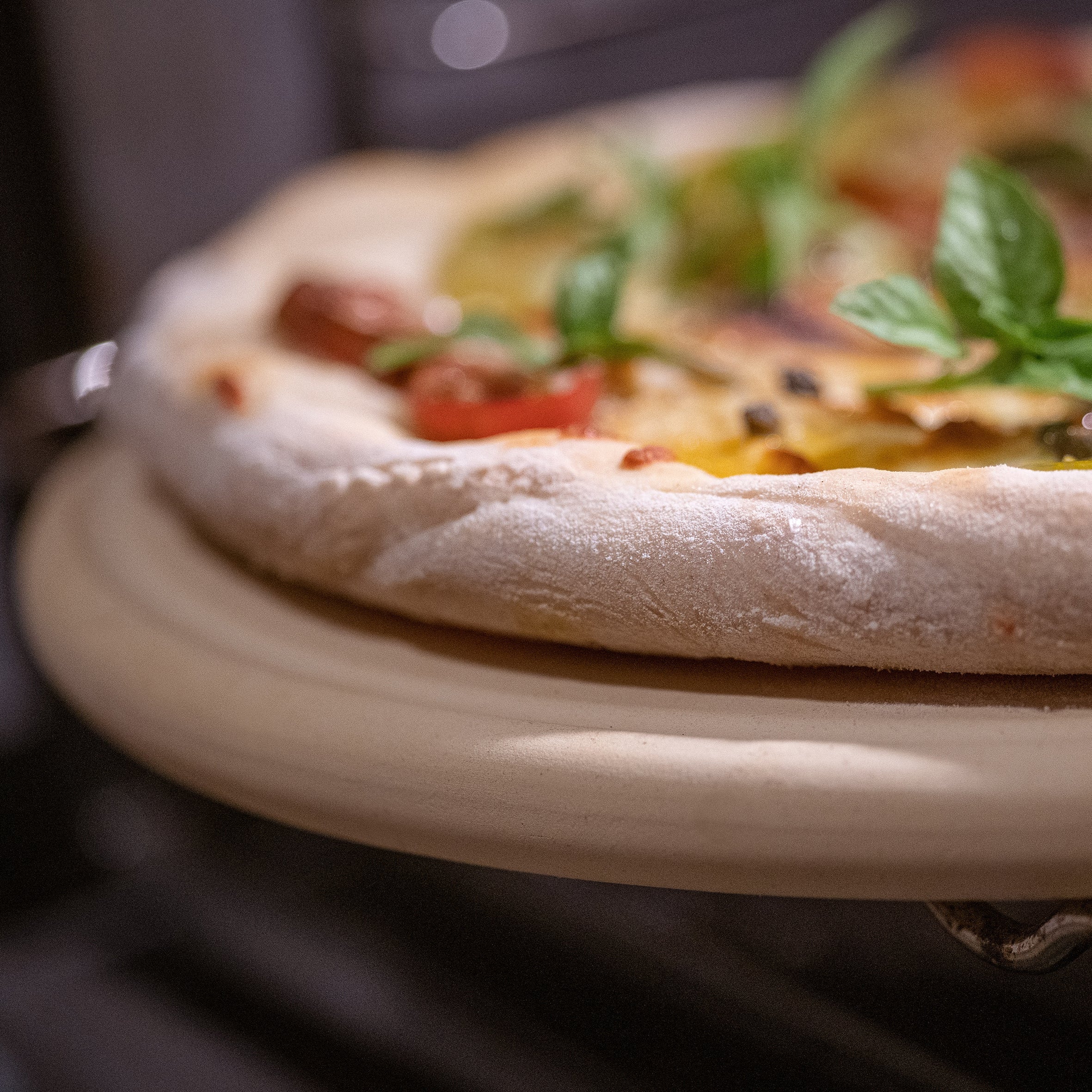 Nahaufnahme der Pizzaplatte von DENK Keramik mit einer Pizza im Ofen
