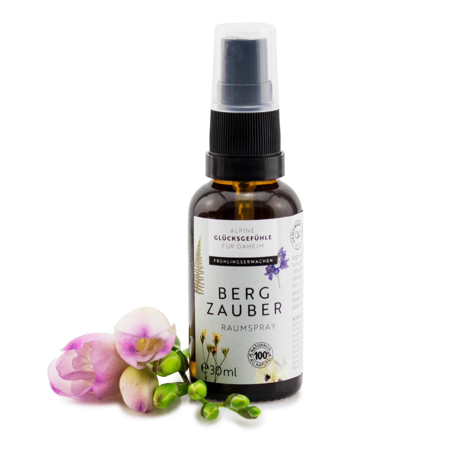 Braune Sprühflasche mit der Aufschrift „Raumspray Bergzauber“ und rosa Blumen auf weißem Hintergrund. Dieses Raumspray neutralisiert Gerüche mit ätherischen Ölen und verleiht jedem Raum eine natürliche Frische.