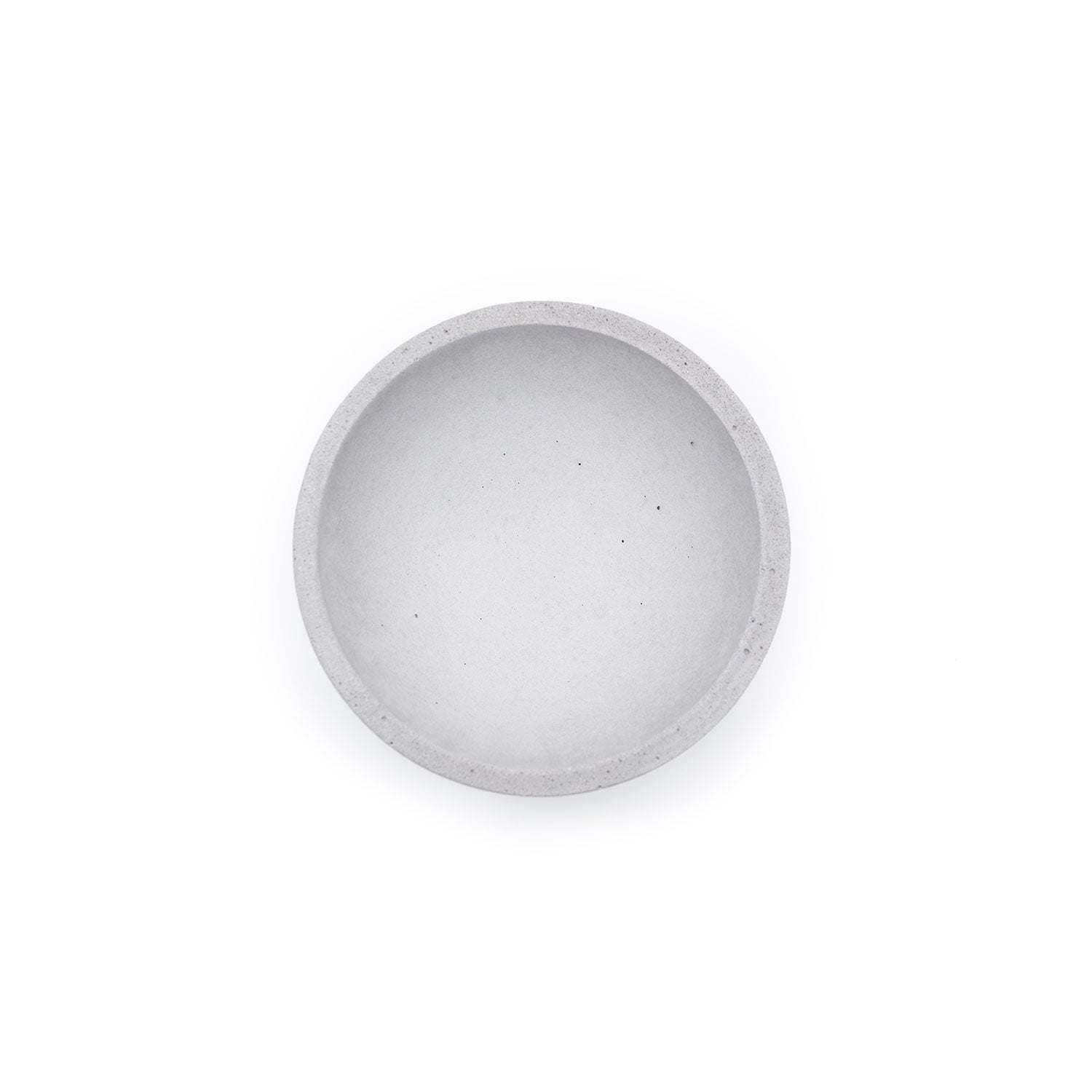 Ein Blick von oben auf eine leere große Betonschale rund auf einem schlichten weißen Hintergrund zeigt ihre glatte Oberfläche, die ihre handwerkliche Qualität und ihr ästhetisches Design unterstreicht.