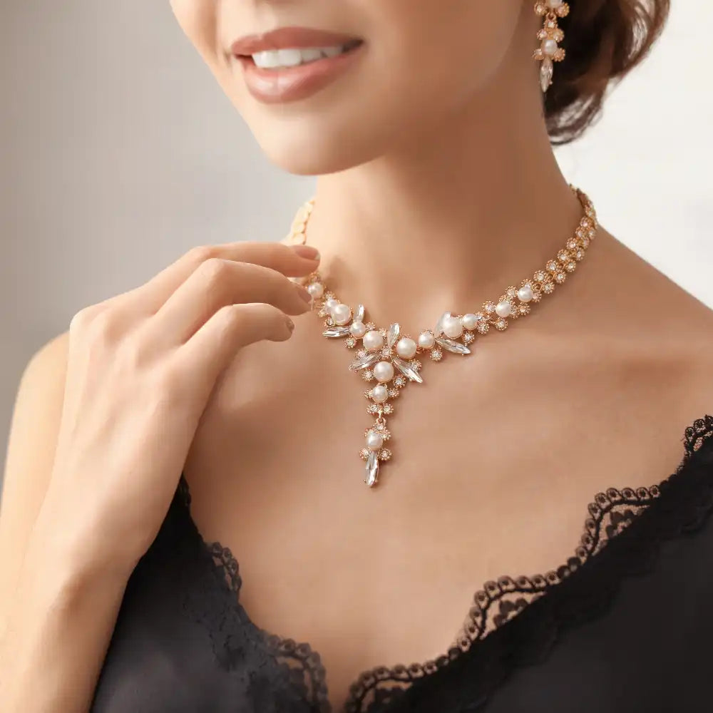 Frau trägt eine Perlen- und Goldkette mit passenden Ohrringen und ein schwarzes Kleid.