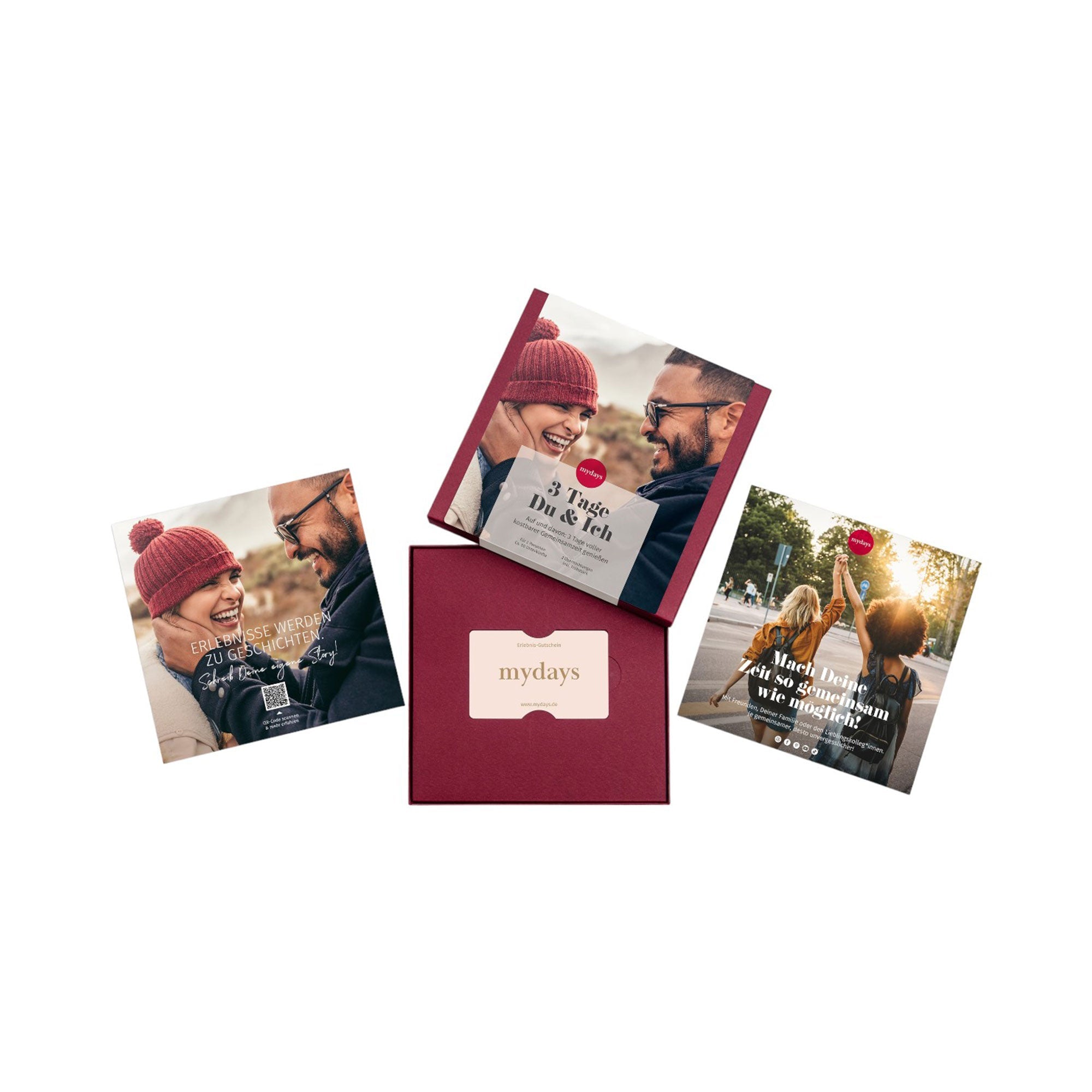 Ein Flatlay präsentiert drei Geschenkkarten und eine rote Box mit der Aufschrift „mydays“. Zwei Karten zeigen ein lächelndes Paar in Winterkleidung. Die Erlebnis-Box „3 Tage Du & Ich“ mit einem Schlitz für einen mydays-Gutschein strahlt Romantik und Weihnachtsstimmung aus.