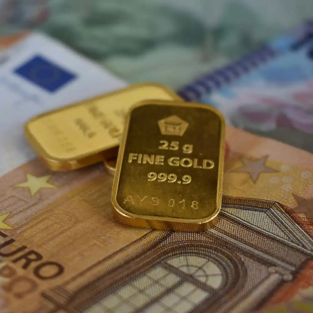 Zwei Goldbarren, die auf Euro-Banknoten liegen.