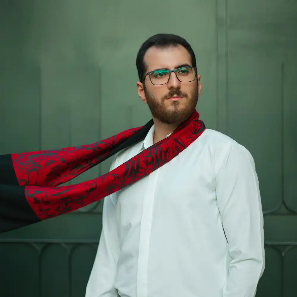 Mann in weißem Hemd und Brille mit rot-schwarzem Schal um den Hals.