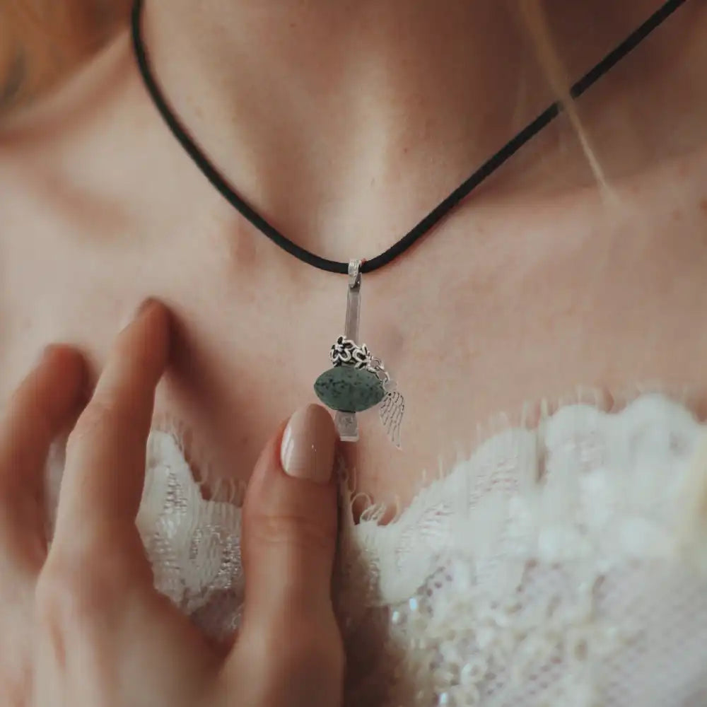 Frau trägt eine schwarze Kordelkette mit einem kleinen Pilzanhänger, der ihre Brust berührt.