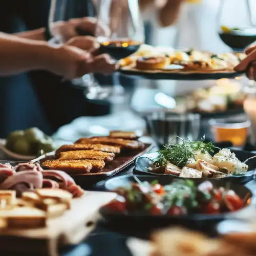 Menschen teilen sich bei einem Abendessen Teller mit verschiedenen Vorspeisen und Wein.