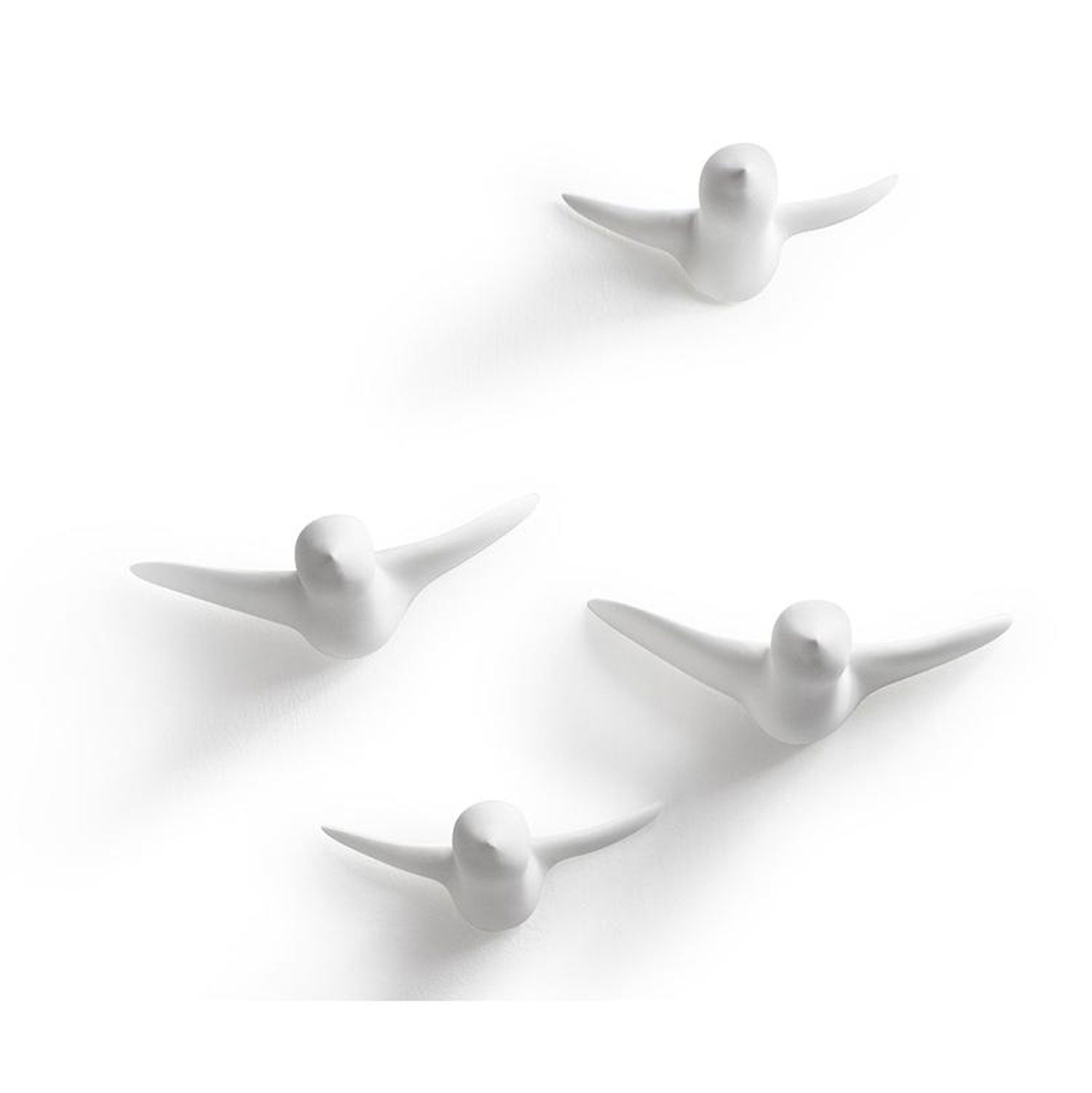Die Wandskulptur - kleiner Vogelschwarm (4 Stk., weiß) besteht aus vier minimalistischen weißen Vogelskulpturen, die an einen Ulmer Spatz erinnern. Sie fliegen vor einem schlichten Hintergrund und werfen weiche Schatten. Jedes Stück verbindet Kunst mit Funktionalität als einzigartiger Wandhaken und verkörpert funktionales Design.