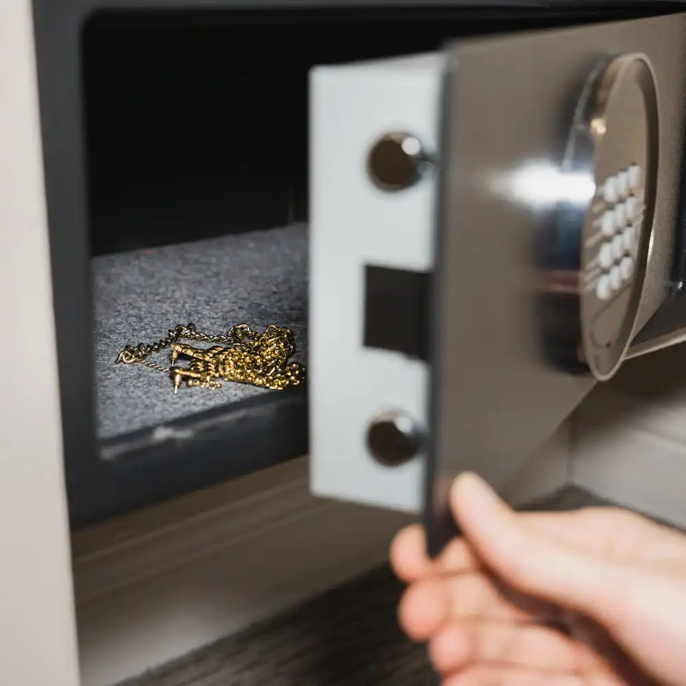 Manuelle Öffnung eines Tresors mit Goldschmuck darin.