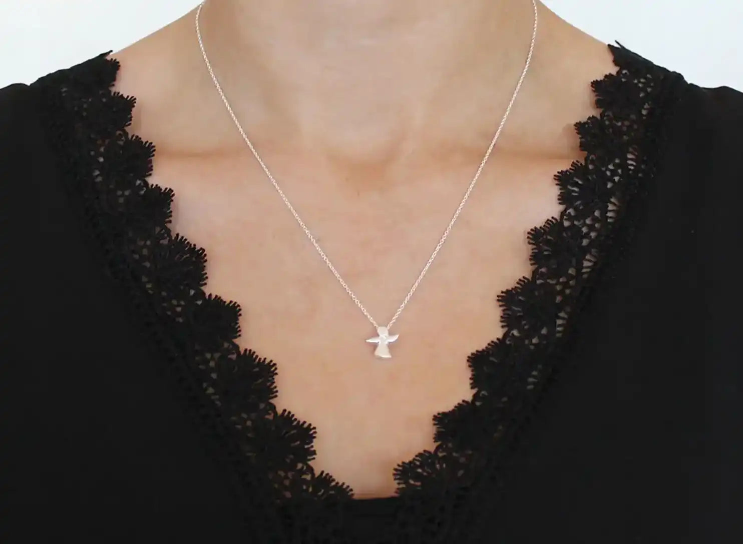 Frau trägt den Kettenanhänger Schutzengel mini mit Kette mit einem schwarzen Oberteil.