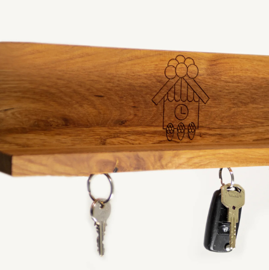 Das magnetische Schlüsselbrett ist ein hölzernes Ulmer Brett mit einem eingravierten kleinen Hausdesign, das drei hängende Schlüsselsätze und ein magnetisches System zur mühelosen Schlüsselaufbewahrung bietet.