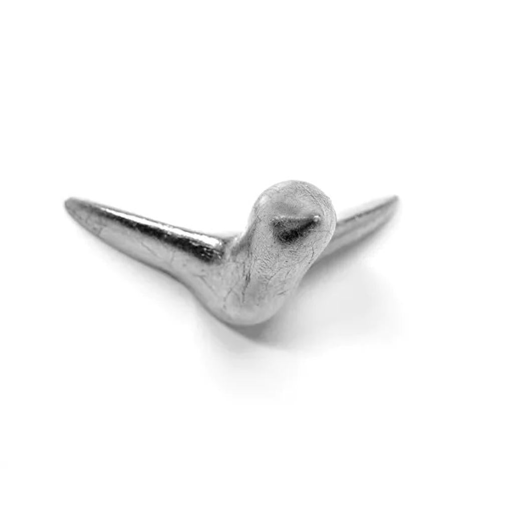 Eine kleine, silberne, vogelförmige Wandskulptur aus Metall „Mini Vogel“ mit ausgebreiteten Flügeln, von oben vor einem weißen Hintergrund betrachtet – perfekt als einzigartige Wanddekoration.