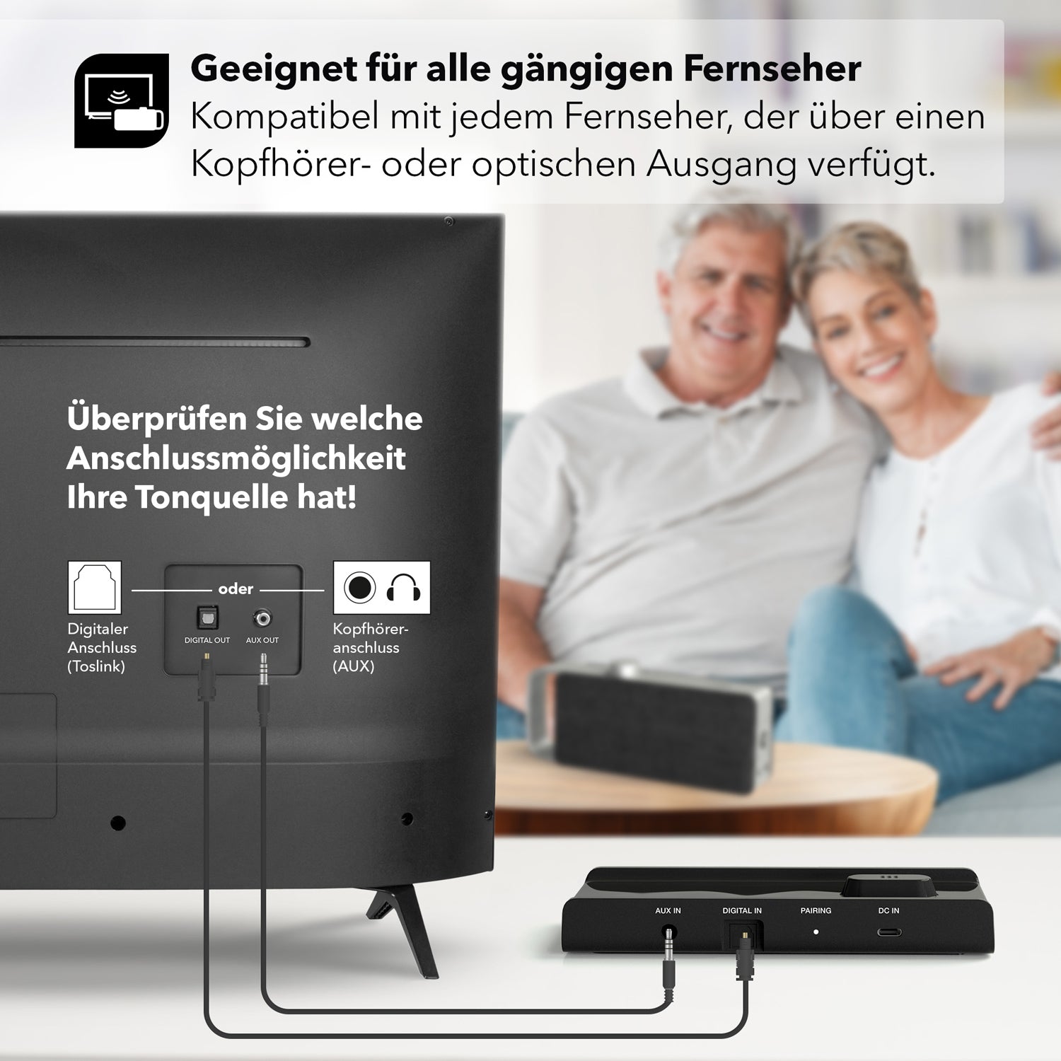 Ein lächelndes Paar sitzt mit einem Smartphone auf dem Sofa neben seinem Fernseher. Der tragbare TV-Sprachverstärker Oskar lässt sich einfach über Digital- oder Kopfhörerausgänge anschließen und verbessert die Klangqualität. Deutscher Text auf dem Bildschirm weist auf Kompatibilität und die Optionen für „Dialog im Fernseher“ hin.