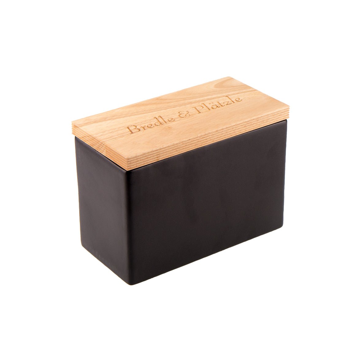 Die Keksdose aus Keramik ist eine rechteckige Brotdose aus Keramik mit einem schlichten schwarzen Korpus und einem hellen Holzdeckel mit der Lasergravur „Brot & Plätzle“, die einen stilvollen Kontrast zwischen dem dunklen Behälter und seinem eleganten Deckel bietet.