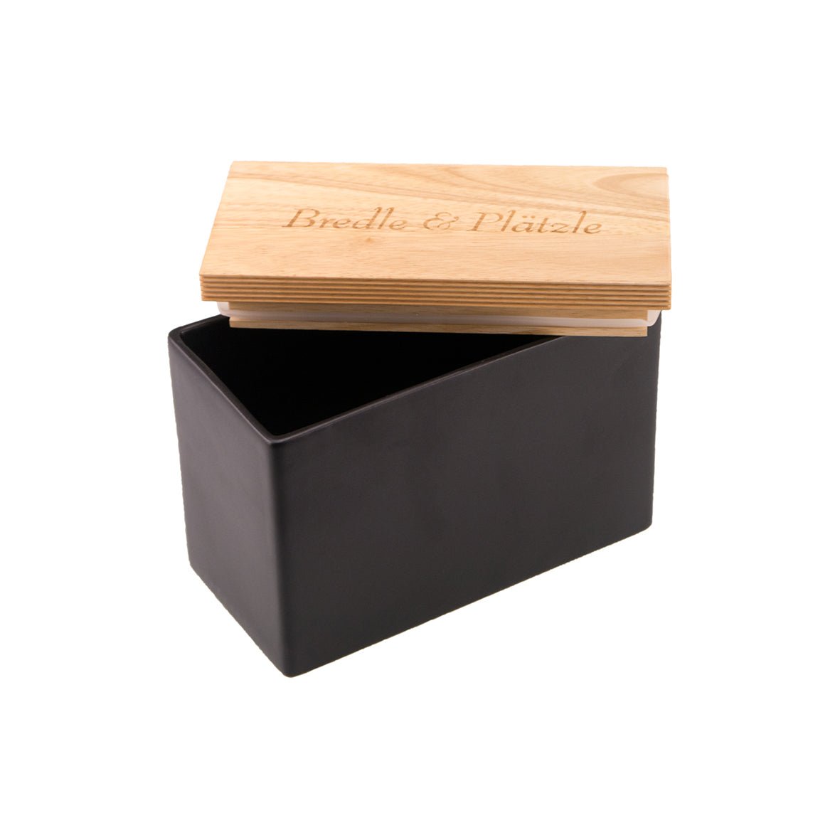 Eine moderne, rechteckige schwarze „Keksdose aus Keramik“ verfügt über einen offenen Holzdeckel und ein schlankes Design mit exquisiter Lasergravur von „Bredle & Plätle“.