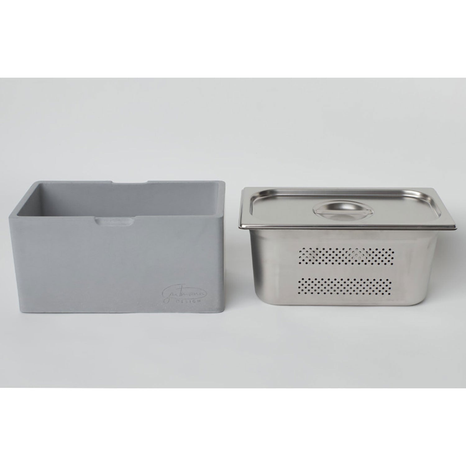 Der Brotkasten mit Edelstahleinsatz & -deckel, bestehend aus einem perforierten Edelstahleinsatz und einem Deckel mit Griff, befindet sich neben der grauen rechteckigen isolierten Brotbox. Seine seitliche Rille macht ihn ideal zur Brotaufbewahrung.