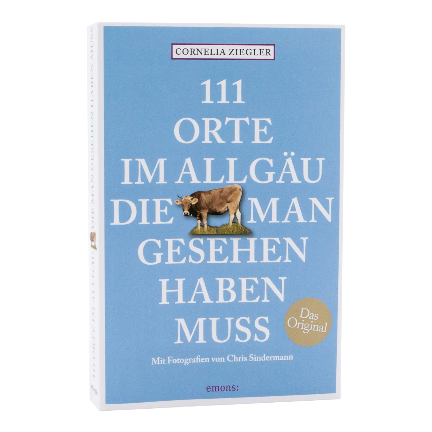 Das Buch „111 Orte im Allgäu, die man gesehen haben muss“ mit hellblauem Einband und einer Kuh, erschienen bei Emons, eignet sich ideal zum Erkunden des Allgäus.