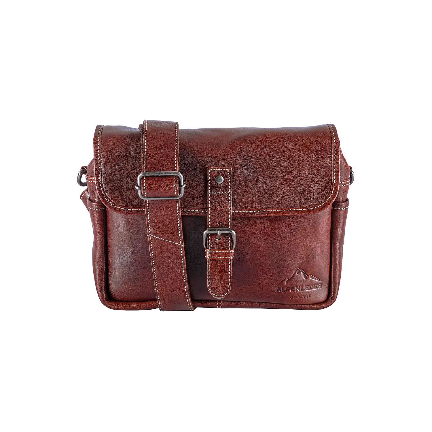 Die Alpenleder Kameratasche PRESSE ist eine braune Leder-Umhängetasche mit Frontklappe und Schnallenverschluss, konzipiert für Hobbyfotografen. Sie verfügt über einen verstellbaren Schultergurt, ein Logo in der unteren rechten Ecke, ein schlankes Design und eine weiche Polsterung für stilvollen Kameraschutz.