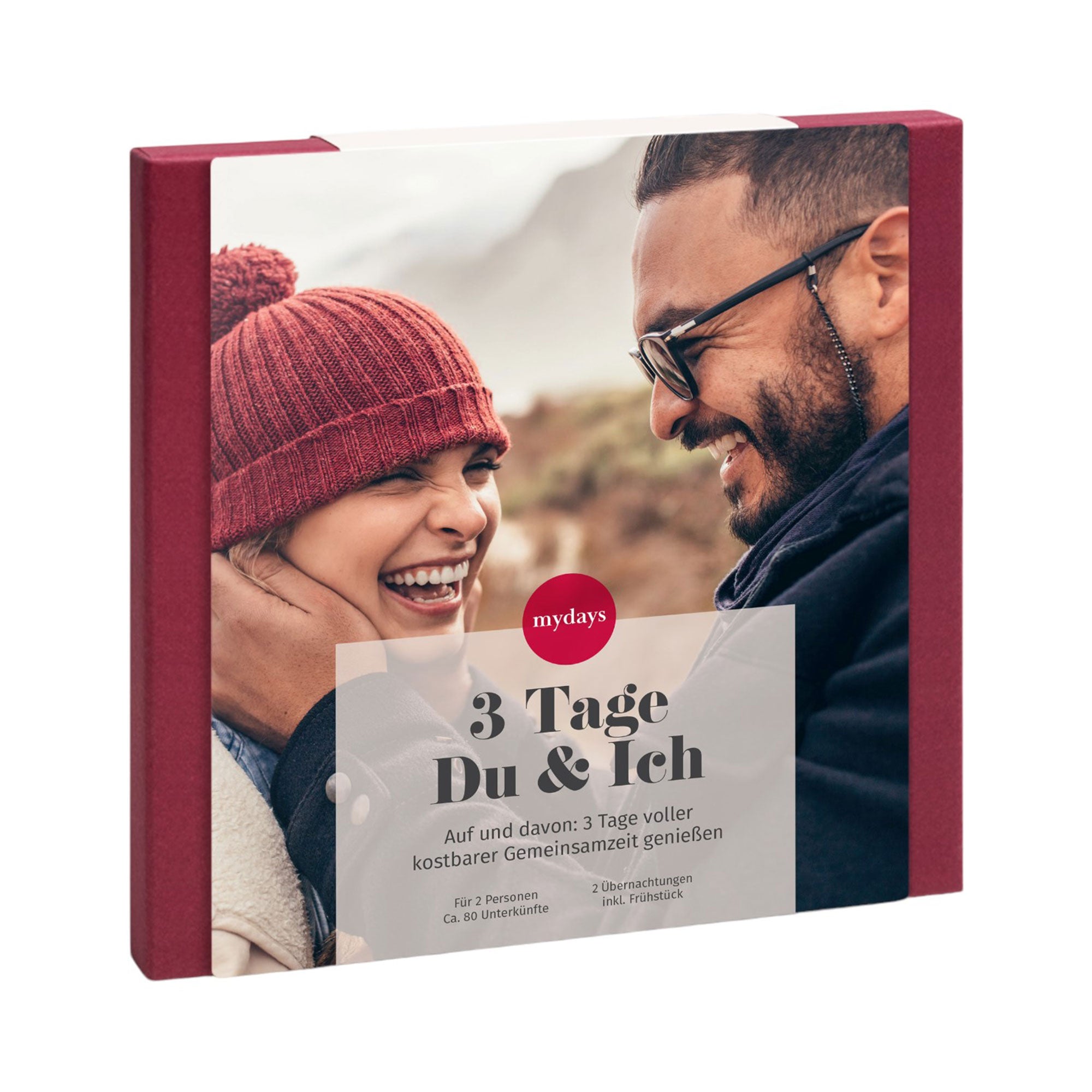 Ein Paar lächelt sich an, eingehüllt in Winterkleidung. Dieses Bild ist Teil der „Erlebnis-Box 3 Tage Du & Ich“ von mydays, die ein Kurzurlaub-Geschenkerlebnis in den Vordergrund stellt. Mit rotem Rand und deutschem Werbetext fängt es wunderschöne gemeinsame Momente ein.