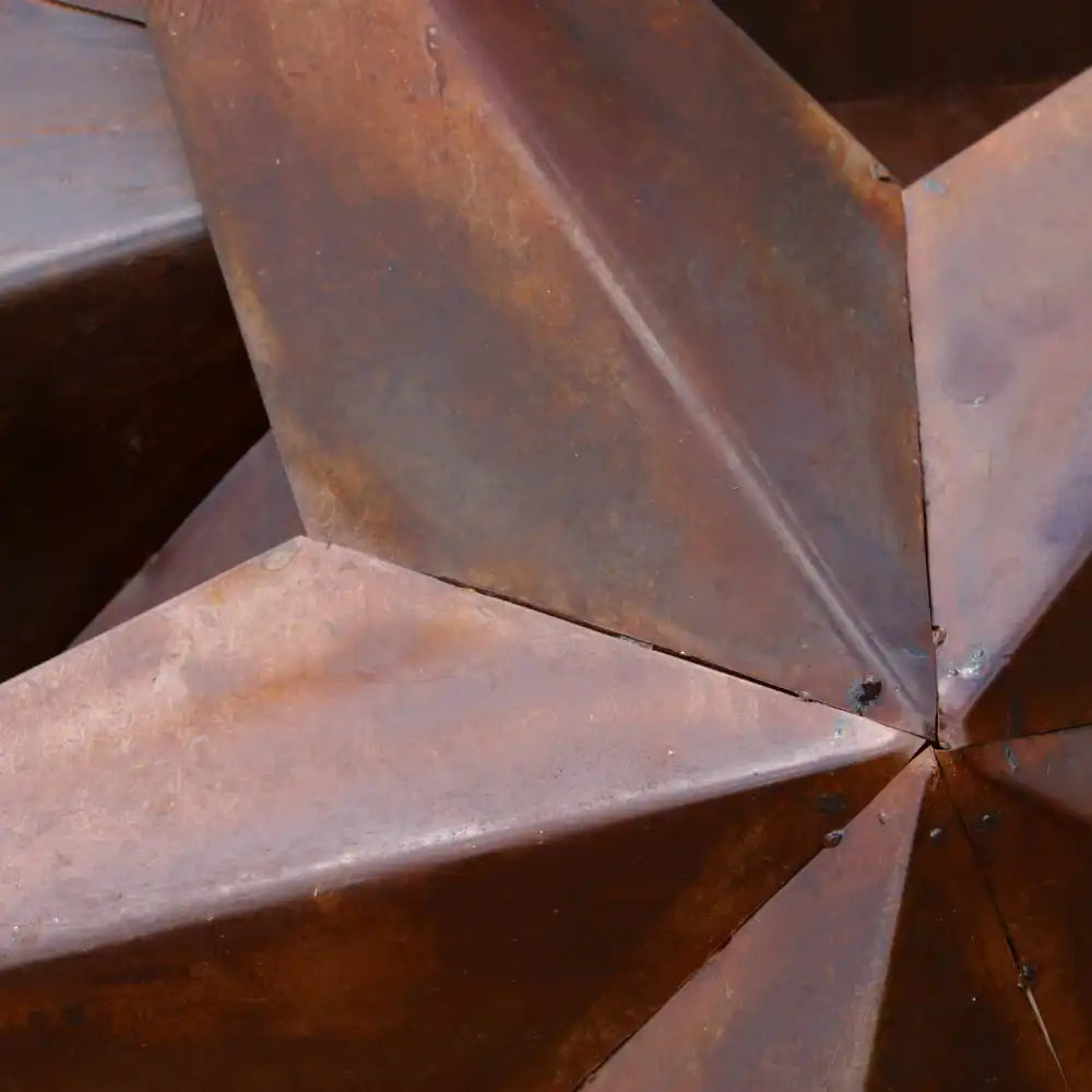 Nahaufnahme von kantigen, verrosteten Metallplatten, die an scharfen Kanten miteinander verbunden sind.