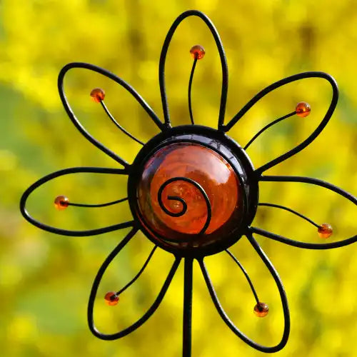 Metallblumen-Gartenornament mit bernsteinfarbener Mitte, vor gelbem Hintergrund.