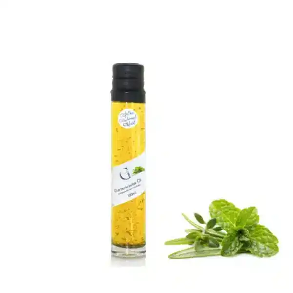 Eine Flasche mit gelbem Öl neben frischer grüner Minze und Kräutern auf weißem Hintergrund.