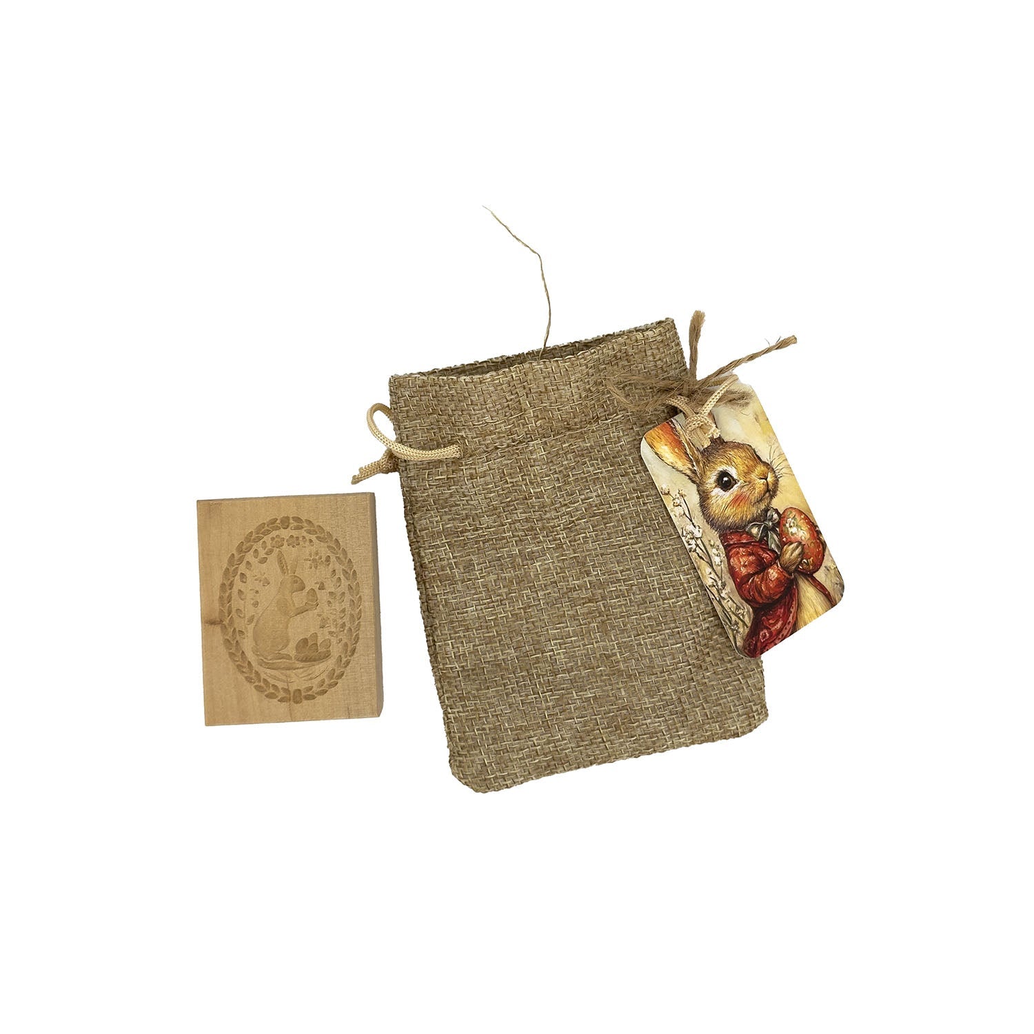 Das Holzspringerle „Osterhase klein“ besteht aus einem Jutebeutel mit Kordelzug und einem Holzanhänger mit einem Hasen in roter Jacke sowie einer gravierten Hasenkarte. Das Design spiegelt die rustikale, naturinspirierte Ästhetik wider und erinnert an den Charme handgeschnitzter Holzspringerle.