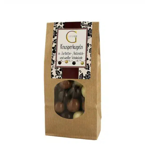 Eine braune Papiertüte mit sortierten Schokoladenkugeln und einem dekorativen Etikett.