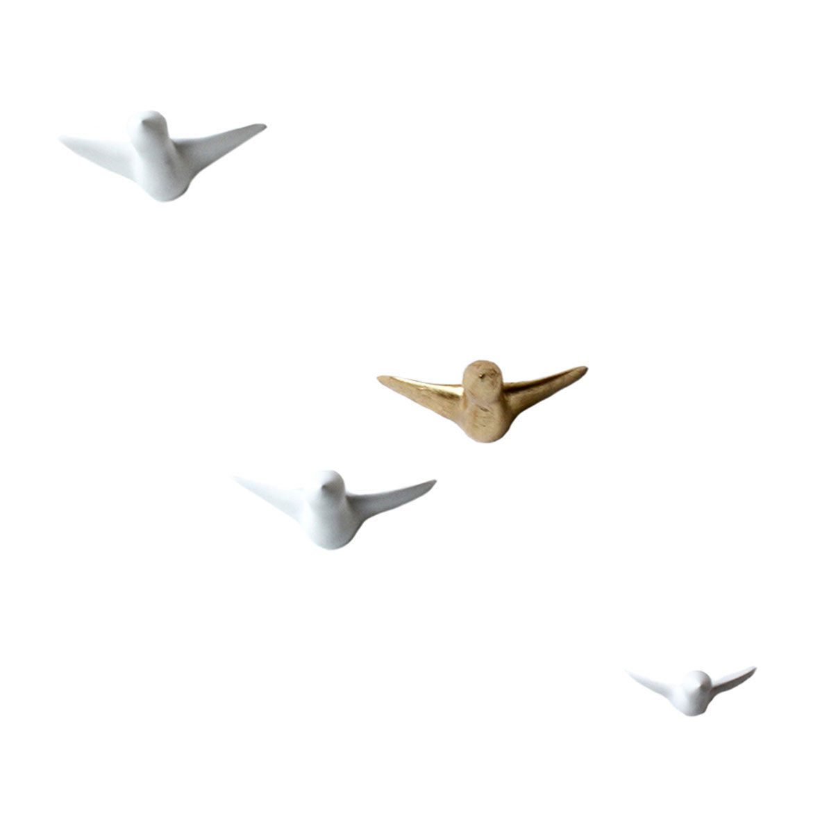 Vier minimalistische Vogelskulpturen in elegantem Design stehen auf weißem Grund. Drei Vögel sind weiß, während ein handgefertigter goldener Vogel zentral positioniert ist und einen markanten Kontrast bildet – eine perfekte Verbindung von Kunst und Funktion, wie die „Wandskulptur – gemischter Vogelschwarm“.