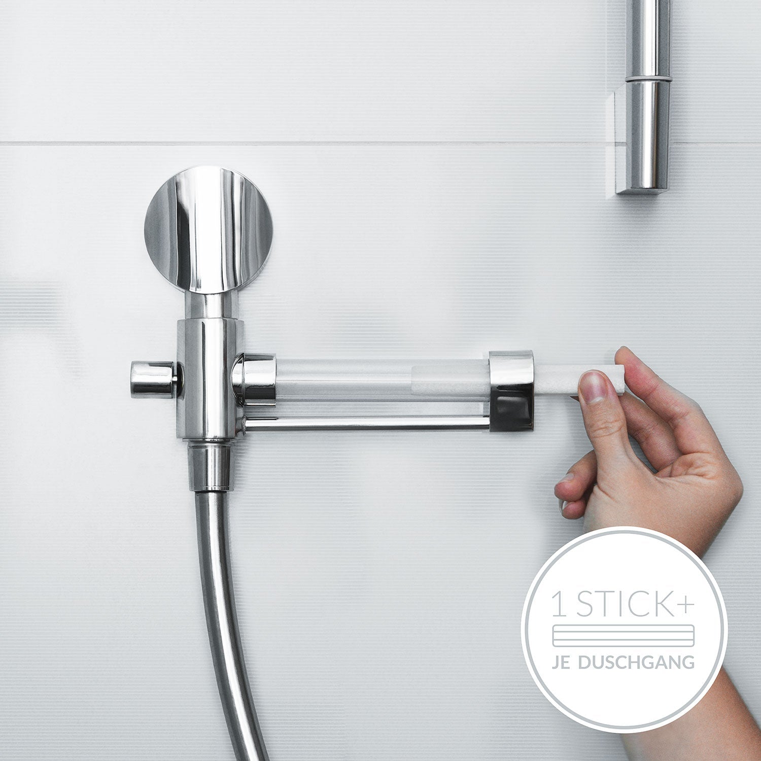 Eine Hand steckt einen Duschstab in die elegante, silberne Duscharmatur vor einer weiß gefliesten Wand. Die durchsichtige Röhre gibt die Essenz von Meersalz frei. Unten rechts steht auf einem runden Logo „1 STICK + JE DUSCHGANG“ – perfekt für empfindliche Haut von „Deine Salzdusche für Zuhause“.