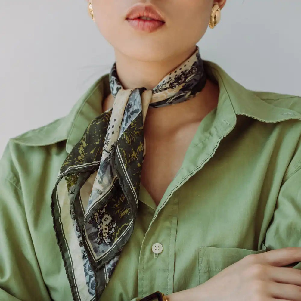 Frau in grünem Hemd und mit einem gemusterten Schal um den Hals gebunden.