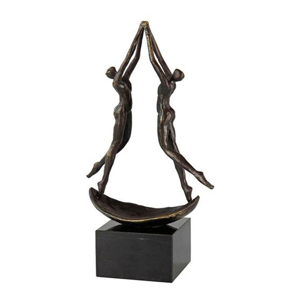 Die Skulptur „Ausgewogenheit“ zeigt zwei abstrakte Bronzefiguren des Künstlers Gerard in einer tanzähnlichen Pose, die nach oben greifen und auf einem kleinen, geschwungenen Sockel auf einem rechteckigen schwarzen Podest balancieren, was Bewegung und Harmonie hervorruft.