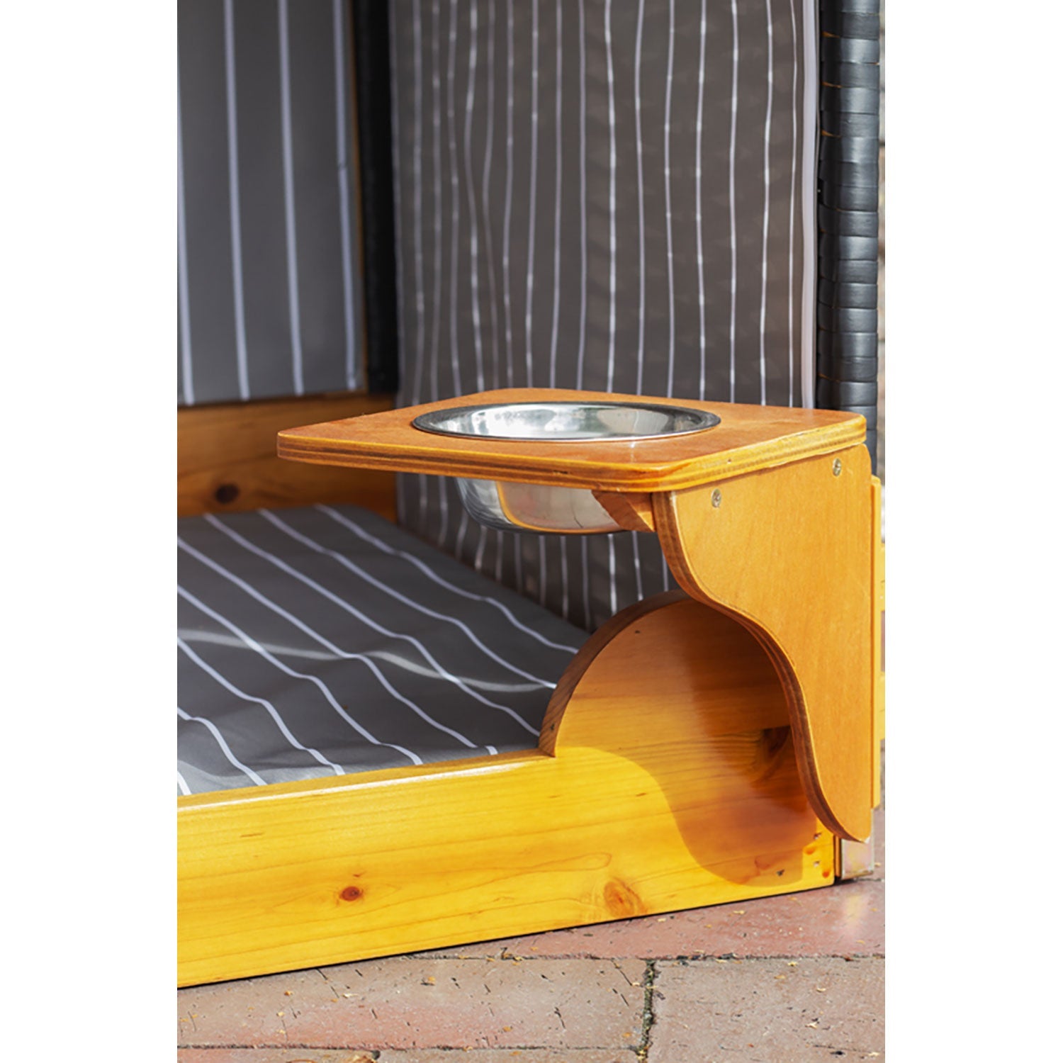 Der Strandkorb für Hunde, anthrazit, ist ein Haustierbett aus hochwertigem Wacholderholz. Es verfügt über einen abnehmbaren Napf auf einem Holzregal, ein gestreiftes Kissen und steht auf einem gefliesten Boden. Stil und Haltbarkeit sind die beiden Elemente für den Komfort Ihres Haustiers.