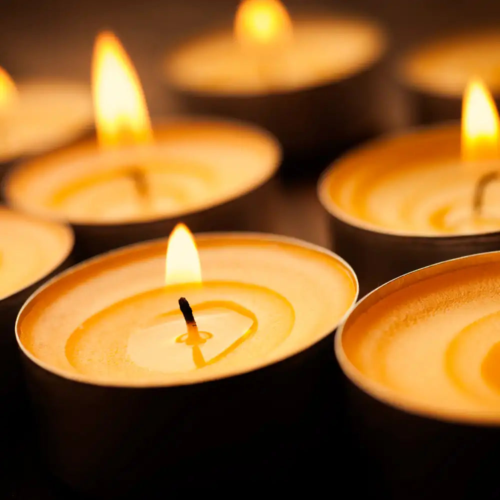 Mehrere brennende Teelichtkerzen leuchten warm in der Nahansicht.