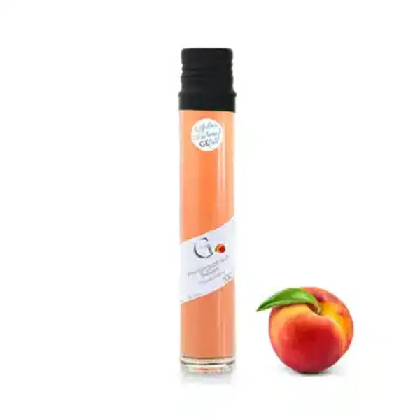 Ein Pfirsich und eine mit Pfirsichsaft gefüllte große Glasflasche auf weißem Hintergrund.